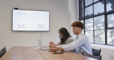 Ekranda verileri sunuyorum. İş kadını, iş arkadaşlarıyla iş yerinde görüşüyor. Sunum, takım çalışması, liderlik, şirket, işbirliği, tartışma