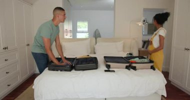 Çeşitli çiftler yatak odasında bavullarını topluyor, birlikte tatile çıkmaya hazırlanıyorlar, evde. Seyahat, bagaj, yolculuk, hazırlık, macera, kaçış