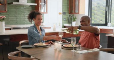 Çeşitli çiftler evde yemek yiyor, şarap dolduruyor ve masada gülücüklerini paylaşıyorlar. Kutlama, toplantı, romantizm