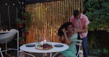 Çeşitli çiftler bahçede romantik bir şekilde yemek yiyorlar. Masada mumlar ve ışıklar var. Aşk, akşam yemeği, atmosfer, bahçede yemek, kutlama