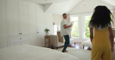 Çeşitli çiftler bavullarını açıyor ve yatak odasında yastıkları düzenliyor, rahat bir ev yaratıyorlar. Taşınma, iç mekan, konfor, yaşam tarzı, yer değiştirme, düzenleme