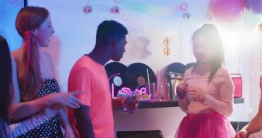 Çeşitli arkadaşlar barda pipetle kokteyl dolduruyor, disko topunun altında dans edip kutluyorlar. Kutlama, yoldaşlık, gece hayatı, canlı, ritim, sosyalleşme, şenlik