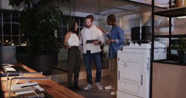 Çeşitli meslektaşlar geceleri yazıcının yanındaki modern ofiste belgeleri tartışıyorlar. İş, takım çalışması, işbirliği, çalışma alanı, teknoloji, üretkenlik