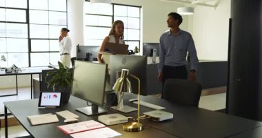 Modern ofisteki çeşitli meslektaşlar proje üzerinde işbirliği yapıyor, gülümsüyor ve fikirleri tartışıyor. İşbirliği, takım çalışması, beyin fırtınası, iş dünyası, profesyonel, takım çalışması