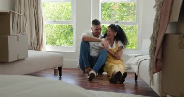 Zeminde oturan farklı bir çift heyecanlı bir şekilde evdeki parlak oturma odasında dizüstü bilgisayarla sohbet ediyorlar. Teknoloji, iletişim, yaşam tarzı, bağlantı, ev, mutluluk