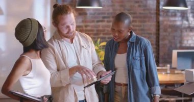 Çeşitli meslektaşlar modern ofiste dijital tabletler kullanarak proje detaylarını tartışıyor. İşbirliği, takım çalışması, teknoloji, beyin fırtınası, işyeri, şirket