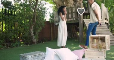 Adam bahçede neşeli bir kadına evlenme teklif ediyor, romantik bir an yaratıyor. Romantizm, nişan, sürpriz, aşk, kutlama, bağlılık