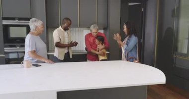 Çeşitli aileler modern mutfakta birlikte eğleniyor, kahkahalar ve kucaklaşmalar paylaşıyorlar. birliktelik, bağlılık, yaşam tarzı, mutluluk, şefkat, ev