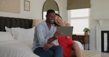 Tablet yerleştirirken çeşitli çiftler yatakta sırayla öpüşüp el sallıyorlar. Romantik, samimiyet, rahatlama, teknoloji, bağlantı, sıcaklık, konfor