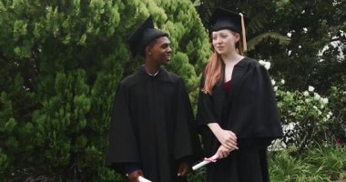 Çeşitli mezuniyet arkadaşları, kampüs çimlerinde el salladıktan sonra kutlama için diplomaları fırlatıyorlar. Kutlama, başarı, dostluk, açık hava, neşe, başarı, kolej