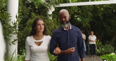 Bahçe partisine yaklaşan Afro-Amerikan çift mücevher kutusu ve kağıt alışverişinde bulunuyor. Açık hava kutlaması, sosyal toplantı, yeşillik, konukseverlik, zarafet, topluluk, eğlence.