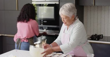 Birlikte kek pişirmek, büyükanne ve torun modern mutfakta gülümsemek, evde. Çeşit çeşit aile, bağ, nesil, gülümseme, yemek pişirme, mutluluk