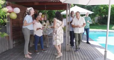 Çeşitli yaşlılar havuz başında eğleniyor, gülüyor ve arkadaşlarıyla sosyalleşiyor. yaşlılar, bahçede, parti, yaz, eğlence, arkadaşlık