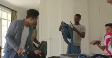 Farklı erkek arkadaşlar, yaşlıları izleyip yatak odasındaki kıyafetleri bavullara ayırıyorlar. İşbirliği, organizasyon, takım çalışması, seyahat, yaşam tarzı, modern, samimi