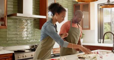 Mutfakta birlikte yemek hazırlayan, önlük giyen ve evde yemek pişirmekten zevk alan bir çift. Mutfak, yemek hazırlama, takım çalışması, yaşam tarzı, ilişki, yerli