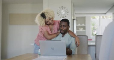 Çeşitli çiftler evde birlikte vakit geçiriyorlar, dizüstü bilgisayara bakarken gülümsüyorlar. Mutluluk, teknoloji, ev hayatı, oturma odası, kaynaşma, boş zaman