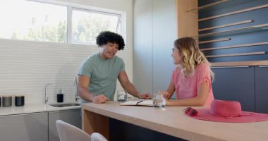 Genç çift mutfak masasında planlarını tartışıyor defter ve içkilerle, evde. Aile içi, yaşam tarzı, planlama, beyin fırtınası, içecek, ilişki