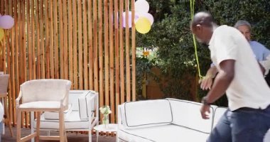 Dışarıda kutlama yapmak, büyükannenin torununa sarılması ve farklı ailelerin birlikte vakit geçirmesi. Kutlama, birliktelik, çok nesilli, mutluluk, bağ, yakınlık