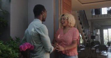 Elinde çiçeklerle arkadaşını selamlayan, gülümseyen ve eğlenen bir kadın. Arkadaşlık, kutlama, buket, mutluluk, konukseverlik, neşe