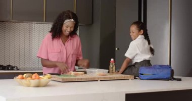 Okul yemeği hazırlıyorum, modern mutfakta anne ve kız, evde sıcak bir şekilde gülümsüyorum. Çeşitli aileler, bağlılık, yemek hazırlığı, mutluluk, yemek pişirme, yaşam tarzı