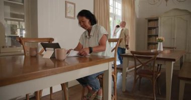 Üst düzey Asyalı çift evde tablet ve akıllı telefon kullanıyor, sabah kahvelerinin tadını çıkarıyorlar. Teknoloji, yaşlılar, yaşam tarzı, iletişim, emeklilik, sabah rutini