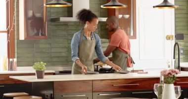 Modern mutfakta birlikte yemek pişiren, önlük giyen ve evde eğlenen farklı çiftler. Takım çalışması, aşçı, yerli, yaşam tarzı