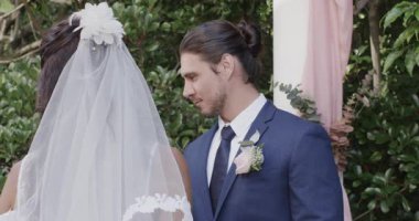 Gelin ve damat, bahçede örtülü pembe kemerin altında düğün yemini okuyorlar. Aşk, kutlama, zarafet, samimiyet, bağlılık, lüks, mutluluk