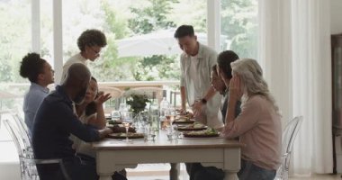 Çeşitli arkadaşlar masada yemeğe başlıyorlar, salata servisi yapıyorlar ve sohbetin ortasında tabakları uzatıyorlar. Yemek, kutlama, yoldaşlık, sosyal, zarafet, açık havada ilham verici, hayat dolu.