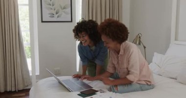 Evde dizüstü bilgisayar kullanırken gülümseyen eş cinsiyetli lezbiyen çift. İlişki, teknoloji, lgbtq, bağlanma, rahatlama, mutluluk