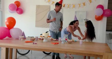 Çeşitli aileler doğum gününü evde doğum günü pastası, parti şapkası ve renkli balonlarla kutluyor. Kutlama, aile, sevinç, heyecan, dekor, festival, toplanma, ikram, etkileşim