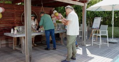 Farklı yaşlılar açık büfede yemek ve kahkahalarla kutlama yapıyorlar. Kutlama, toplantı, arka bahçede yemek, topluluk, parti, şenlik