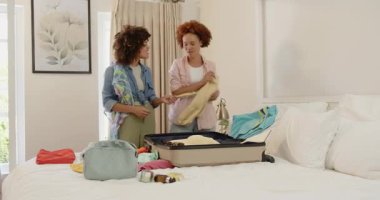 Lezbiyen çift yataklarına bavul hazırlıyor, evde heyecanlı bir tatil için hazırlanıyorlar. Seyahat, bagaj, macera, kaçış, hazırlık, yolculuk