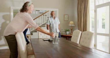 Çeşitli yaşlılar evde kutlama için yemek masası hazırlıyorlar, bardakları ve içecekleri düzenliyorlar. Toplanma, konukseverlik, yaşam tarzı, birliktelik, hazırlık, dekorasyon