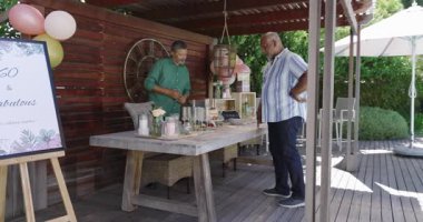 Bahçe partisi masasında hazırlanırken iki farklı son sınıf öğrencisi balonlarla süslenip kutlama yapıyor. Kutlama, şenlik, takım çalışması, arkadaşlık, çeşitlilik, toplanma