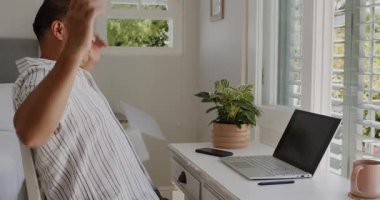 Üst düzey bir adam dizüstü bilgisayarla masada oturuyor, pencereden dışarı bakarken gülümsüyor, evde. Teknoloji, olgunluk, mutluluk, tefekkür, boş zaman, çalışma alanı