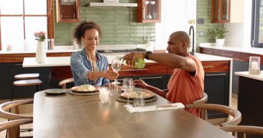 Çeşitli çiftler evde akşam yemeğinin tadını çıkarıyor, şarap dolduruyor ve neşeli anları paylaşıyorlar. Romantik, yemek, kutlama, mutluluk, yaşam tarzı, içki