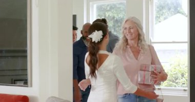 Asyalı gelin yemek odasına giriyor, yaşlı kadına sarılıyor, parti için şarap kadehleri hazırlıyor. Kutlama, aile, toplanma, konukseverlik, sıcaklık, zarafet, sosyalleşme