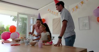 Çeşitli aileler çocuklarının doğum gününü pencerelerle kutluyor, evde pasta ve neşeyle servis ediyorlar. Kutlama, parti, pasta, aile, eğlence, şenlik, coşku, balonlar