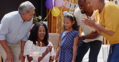 Üç farklı nesil doğum gününü kutlarken genç kız evde keklerin üzerine mum üflüyor. Çeşit çeşit aile, kutlama, mutluluk, birliktelik, çoklu nesiller arası bağ