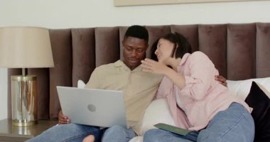 Yolculuk planı yapan çift dizüstü bilgisayarı kontrol ediyor ve yataktan kalkış kartını heyecanla alkışlıyor. Romantizm, bağlantı, heyecan, eğlence, samimiyet, uyum, iletişim