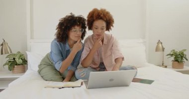 Evde dizüstü bilgisayar kullanırken aynı cinsiyetten lezbiyen çift birlikte gülüyor. LGBTQ, teknoloji, çevrimiçi, yaşam tarzı, yerli, kahkaha