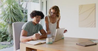 Evde dizüstü bilgisayar ve defter kullanarak proje üzerinde işbirliği yapan genç bir çift var. İşbirliği, takım çalışması, uzaktan çalışma, beyin fırtınası, yaratıcılık, teknoloji