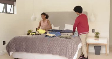 Çeşitli aileler, heyecan verici bir tatil gezisine hazırlanmak için bavullarını yatakta topluyor. seyahat, hazırlık, heyecan, bağ