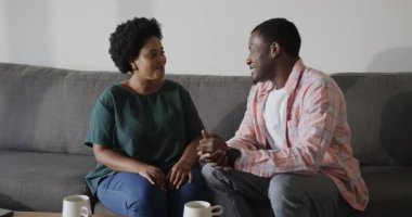 Adam yüzükle koltukta heyecanlı bir kadına evlenme teklif ediyor. İkisi de sevinçle gülümsüyor. Nişan, evlilik teklifi, romantizm, aşk, kutlama, mutluluk