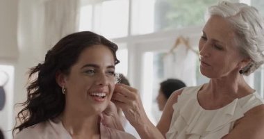 Kıdemli kadın altın halkalar seçiyor ve onları takıyor. Sonra da düğün için kızına sarılıyor. Zarafet, samimiyet, duygusallık, ustalık, kutlama, şefkat, moda.