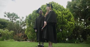 Çeşitli arkadaşlar çimenlikte diploma taşıyorlar, karşılıklı konuşuyorlar mezuniyet münasebetiyle havan topu atıyorlar. Kutlama, başarı, yoldaşlık, açık hava, gençlik, şenlik, başarı