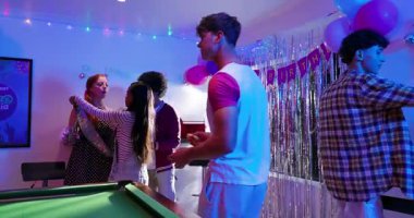 Çeşitli arkadaşlar parti odasında hediyeler dağıtıp kuşak takıp selfie çekiyorlar. Kutlama, arkadaşlık, sosyal, eğlence, coşku, parti, neşe