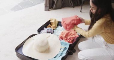 Bavulu açmak, kıyafetleri sıralayan kadın, ev halısında tıkırdayan liste, yolculuk için hazırlanma, fotokopi alanı. Seyahat paketleri, organizasyon, yaşam tarzı, minimalizm, ev içi, tatil hazırlığı, gündelik