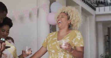 Çeşitli arkadaşlar şen şakrak bir kutlama sırasında evde gülüp içkinin tadını çıkarıyorlar. parti, içecekler, kahkahalar, toplanma, eğlence, şenlik