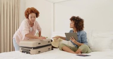 Lezbiyen çift yataklarına bavul hazırlıyor, evde heyecanlı bir tatil için hazırlanıyorlar. Seyahat, bagaj, tatil, yolculuk, hazırlık, macera